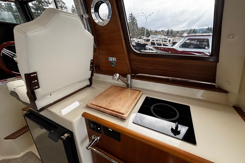  Yacht Photos Pics Interior of 2026 Ranger Tugs R-25, featuring compact kitchen with stove and cutting board.