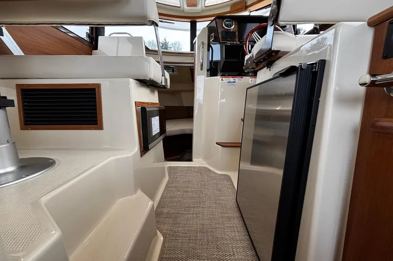  Yacht Photos Pics Interior of 2026 Ranger Tugs R-25 boat, featuring seating and compact kitchen area.