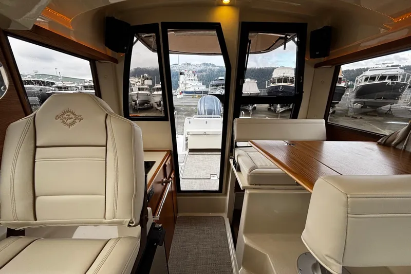  Yacht Photos Pics Interior of 2026 Ranger Tugs R-25 boat with seating and table, docked at marina.
