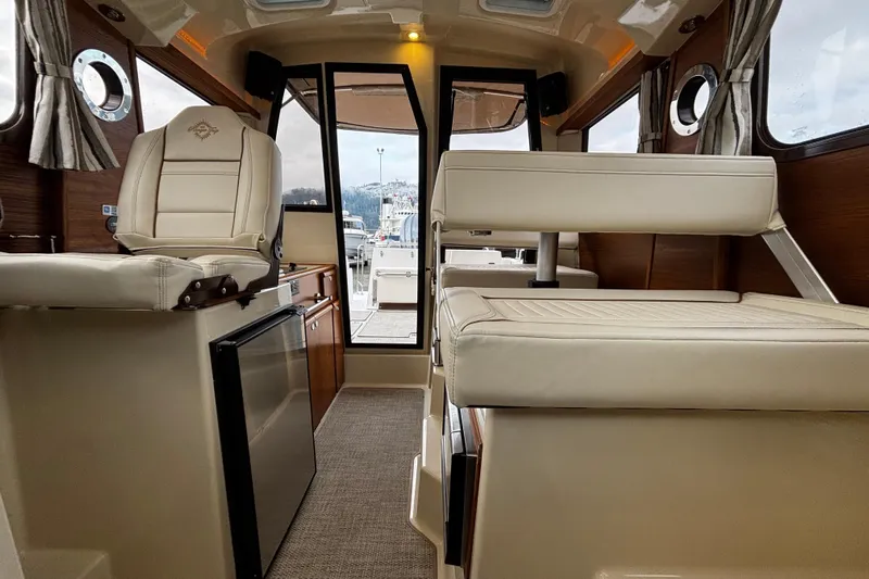  Yacht Photos Pics 2026 Ranger Tugs R-25 interior with beige seating, compact fridge, and large windows.