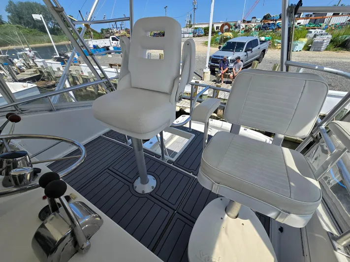  Yacht Photos Pics Helm seating on 1998 Henriques 38 Sportfisherman, featuring white captain chairs and controls.