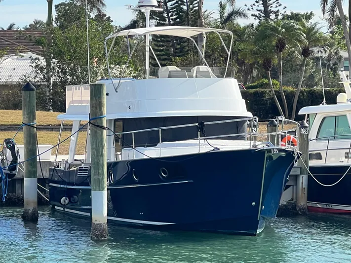  Yacht Photos Pics 2019 Beneteau Swift Trawler 44 docked in a marina, surrounded by lush greenery.