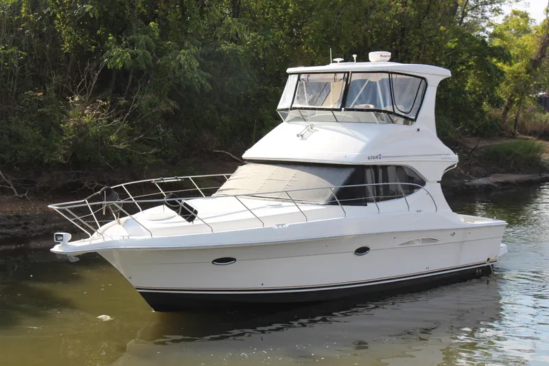  Yacht Photos Pics 2003 Silverton 38 Convertible yacht on calm water, surrounded by lush greenery.