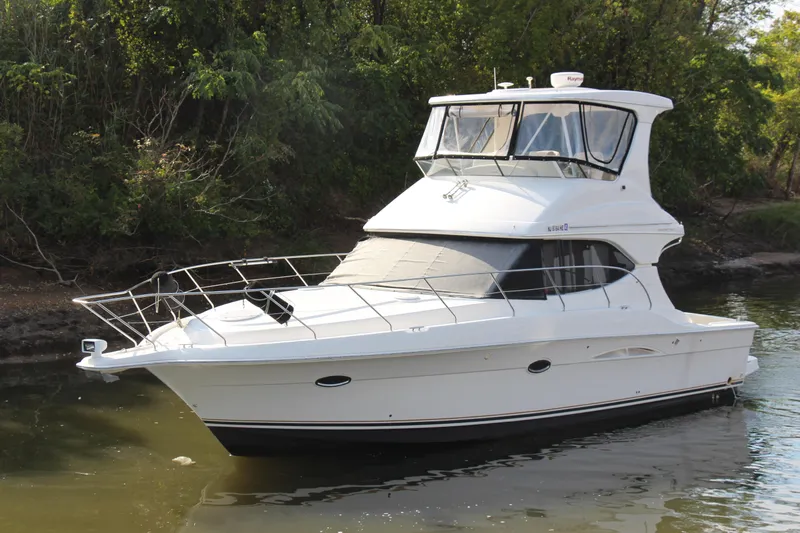  Yacht Photos Pics 2003 Silverton 38 Convertible yacht on calm water, surrounded by lush greenery.