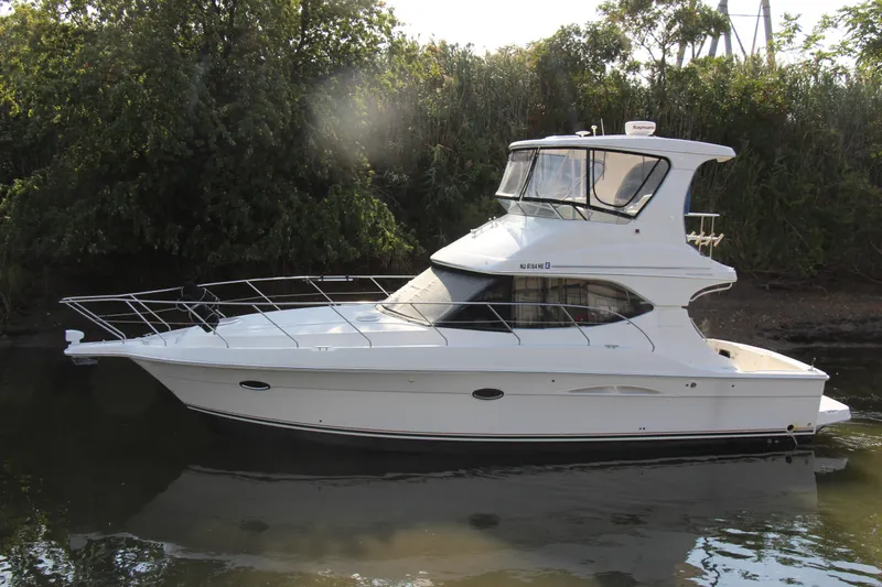  Yacht Photos Pics 2003 Silverton 38 Convertible yacht on calm water, surrounded by lush greenery.