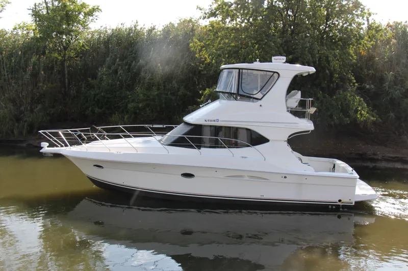  Yacht Photos Pics 2003 Silverton 38 Convertible yacht cruising on a calm river, surrounded by lush greenery.