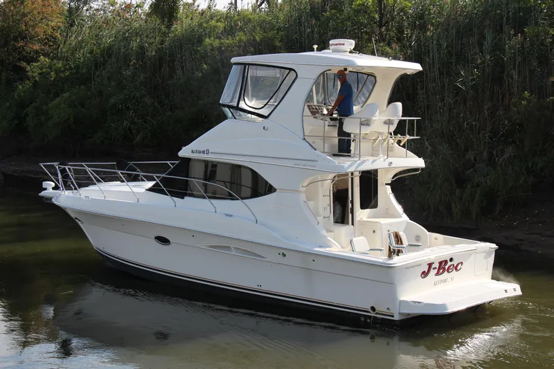  Yacht Photos Pics 2003 Silverton 38 Convertible yacht cruising on a calm river, surrounded by lush greenery.
