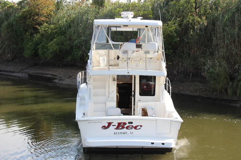  Yacht Photos Pics 2003 Silverton 38 Convertible boat navigating a narrow waterway, surrounded by lush greenery.