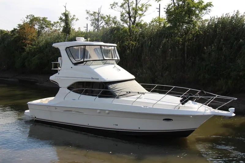  Yacht Photos Pics 2003 Silverton 38 Convertible yacht on calm water, surrounded by lush greenery.