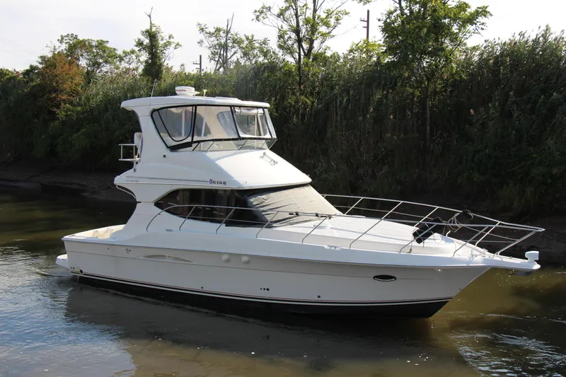  Yacht Photos Pics 2003 Silverton 38 Convertible yacht on calm water, surrounded by lush greenery.