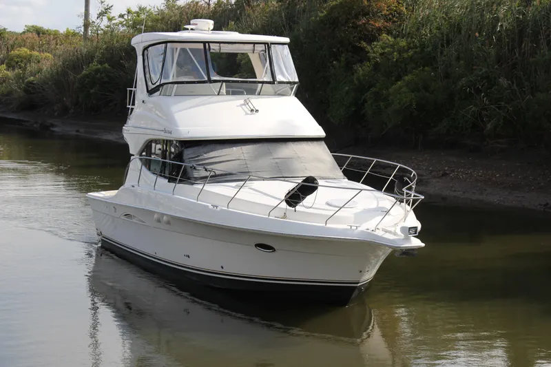 Yacht Photos Pics 2003 Silverton 38 Convertible yacht cruising on a calm river, surrounded by lush greenery.