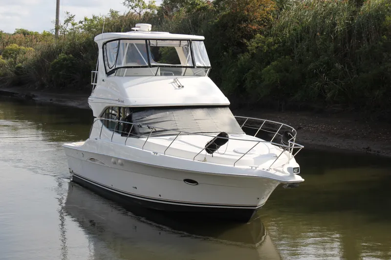  Yacht Photos Pics 2003 Silverton 38 Convertible yacht cruising on a calm river, surrounded by lush greenery.