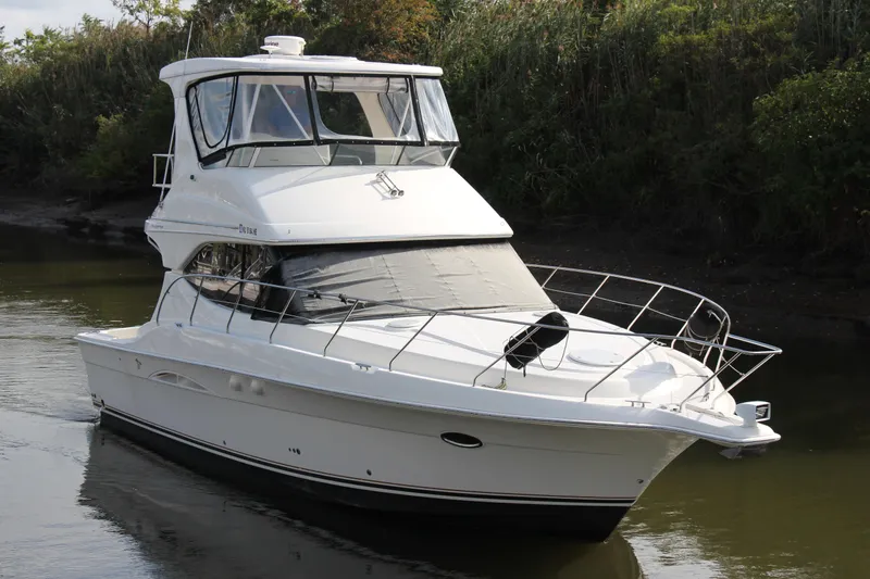  Yacht Photos Pics 2003 Silverton 38 Convertible yacht cruising on a calm river, surrounded by lush greenery.