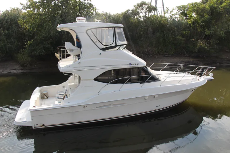  Yacht Photos Pics 2003 Silverton 38 Convertible yacht on calm water, surrounded by lush greenery.