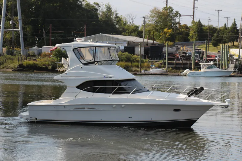  Yacht Photos Pics 2003 Silverton 38 Convertible yacht cruising on a calm river near a marina.