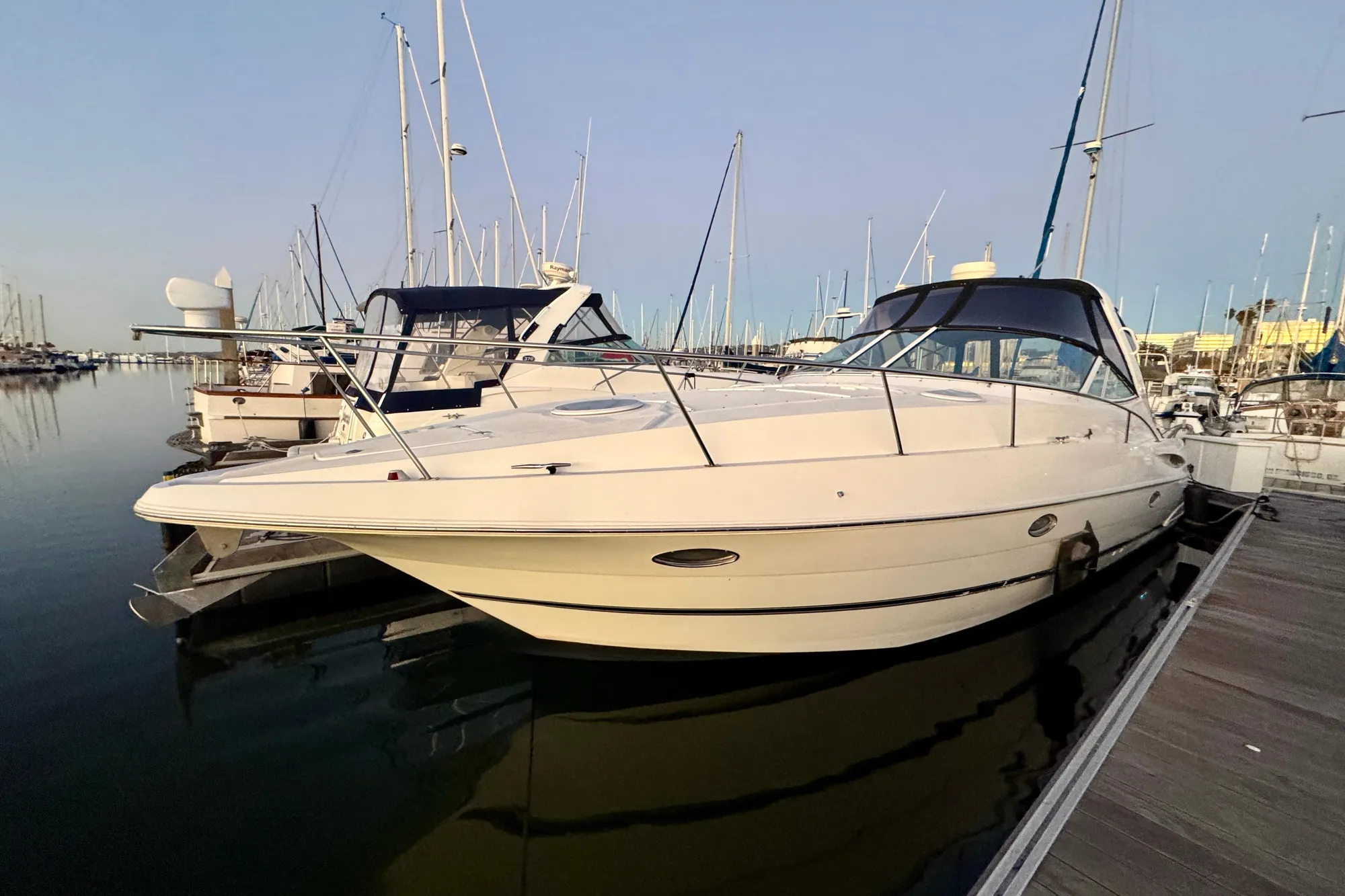 2001 Cruisers Yachts 3470 Express docked in a marina, surrounded by sailboats.