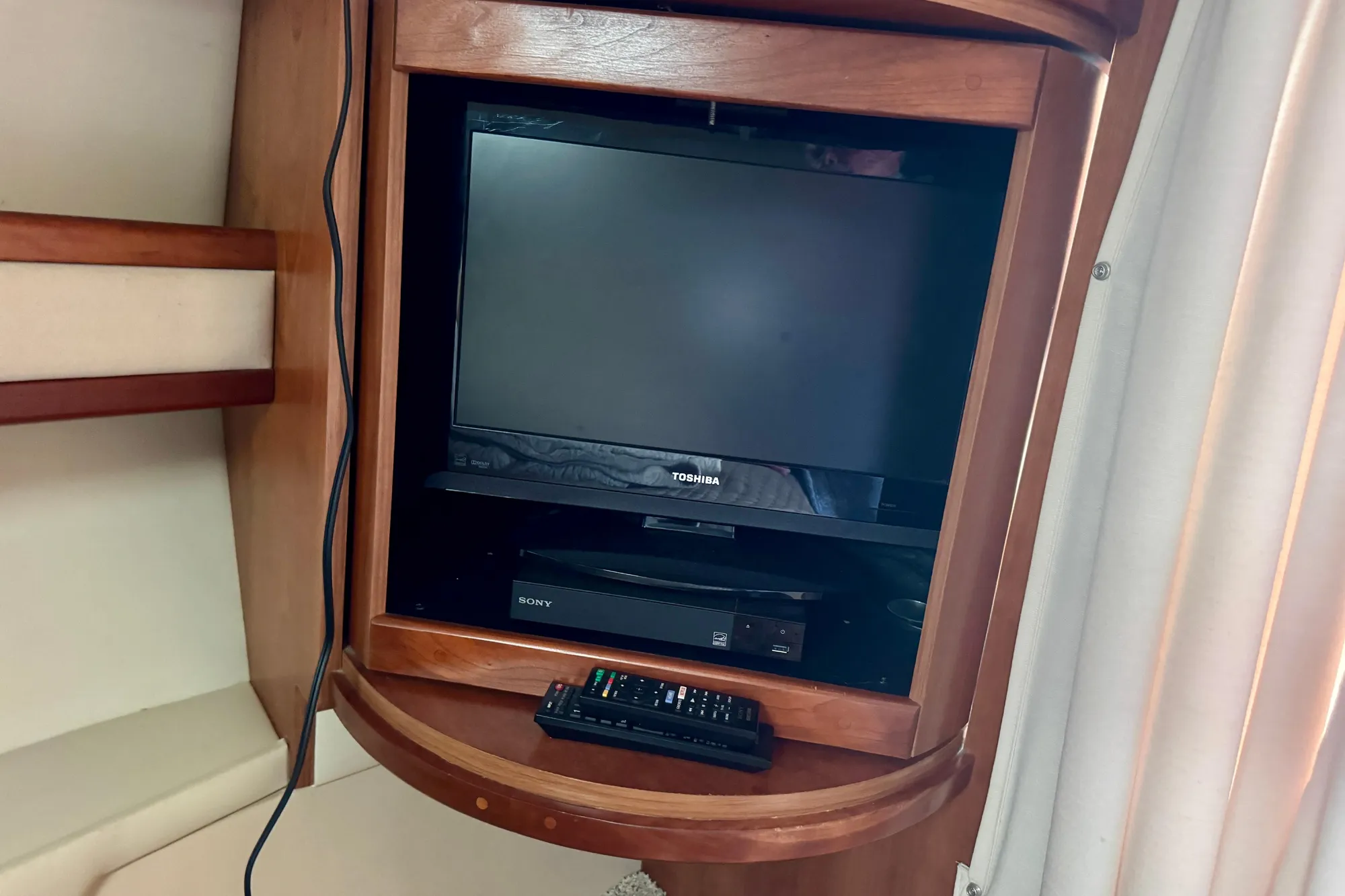 Entertainment setup in 2001 Cruisers Yachts 3470 Express cabin with TV and remote.
