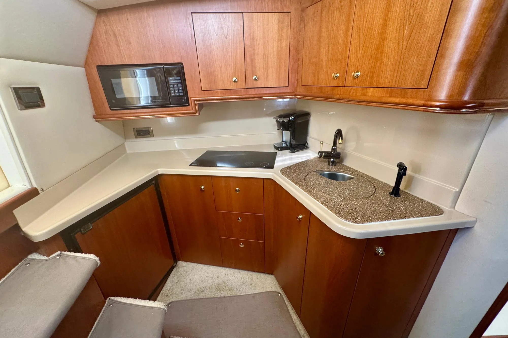 2001 Cruisers Yachts 3470 Express kitchen with microwave, stove, sink, and wooden cabinetry.
