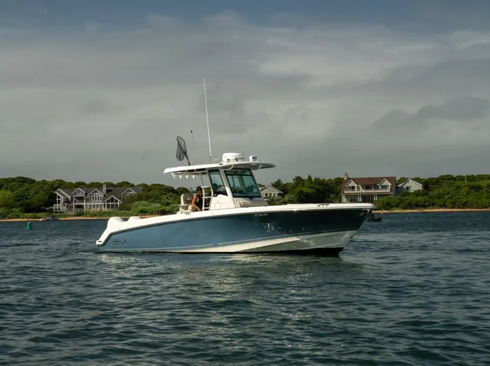 Just Wednesdays Yacht Photos Pics 2022 Boston Whaler 330 Outrage boat cruising on a calm lake near shoreline homes.