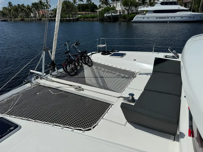  Yacht Photos Pics 2023 Lagoon 42 catamaran with netted deck, bicycles, and waterfront view.