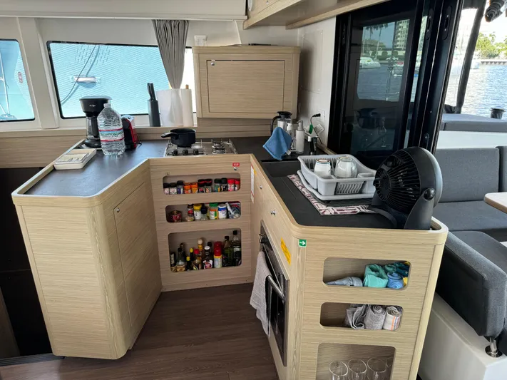  Yacht Photos Pics Modern kitchen interior of 2023 Lagoon 42 catamaran with organized shelves and appliances.