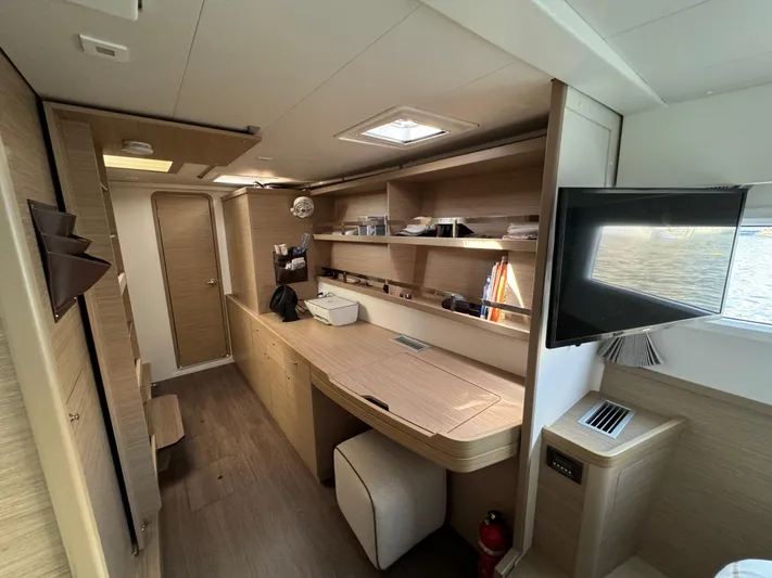  Yacht Photos Pics Modern interior of 2023 Lagoon 42 yacht with wooden cabinetry and mounted TV.