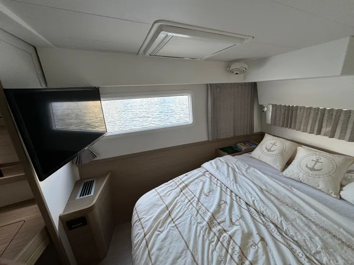  Yacht Photos Pics Luxurious cabin interior of 2023 Lagoon 42 yacht with cozy bedding and window view.