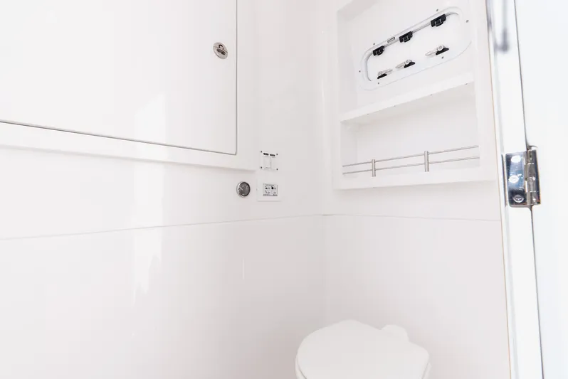  Yacht Photos Pics 2024 Intrepid 427 Nomad SE boat bathroom with white interior and storage shelves.