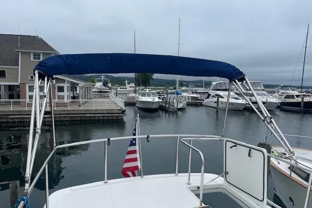  Yacht Photos Pics American Tug 365 (2018) docked at a marina with a blue canopy and American flag.