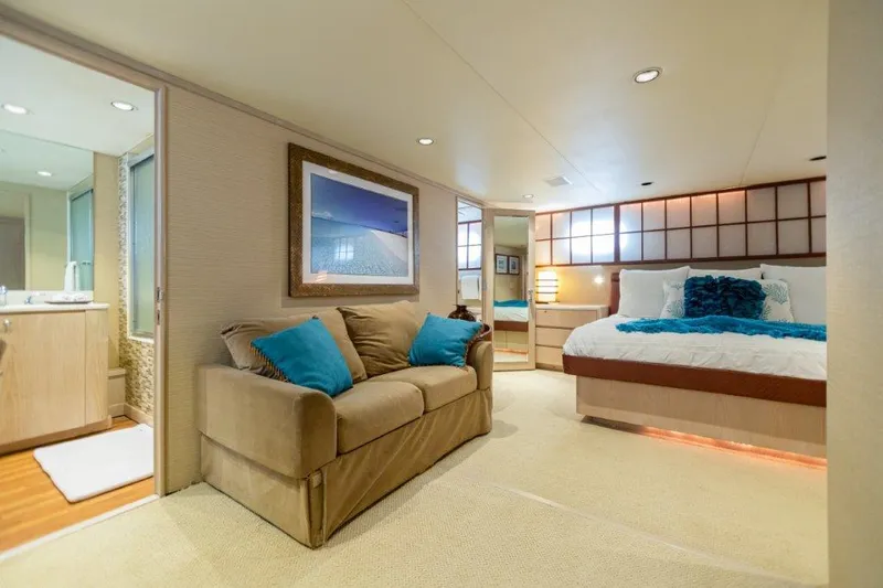 Island Time Yacht Photos Pics Luxurious bedroom in a 1991 Broward Motor Yacht with ensuite bathroom and cozy seating area.