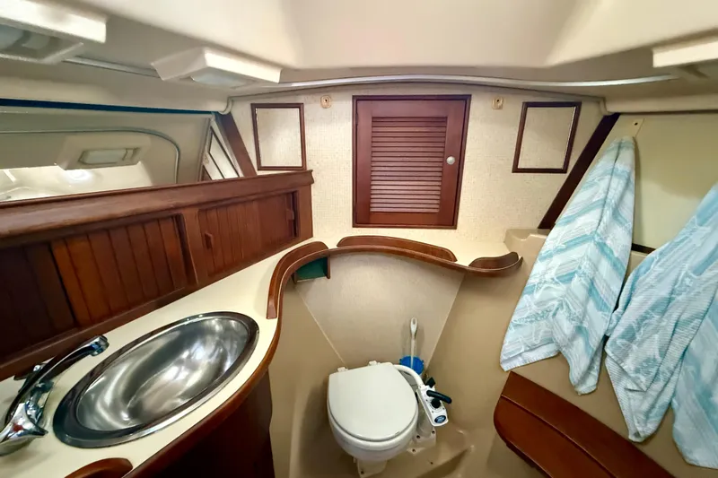 Blue Skies Yacht Photos Pics 1995 Island Packet 40 yacht bathroom with sink, toilet, and wooden cabinetry.
