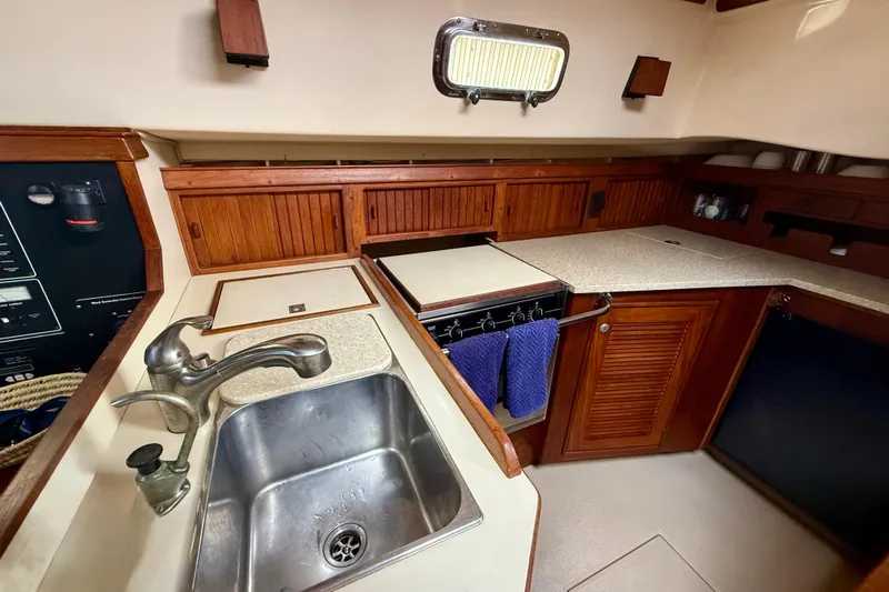 Blue Skies Yacht Photos Pics 1995 Island Packet 40 yacht kitchen with sink, stove, and wooden cabinetry.