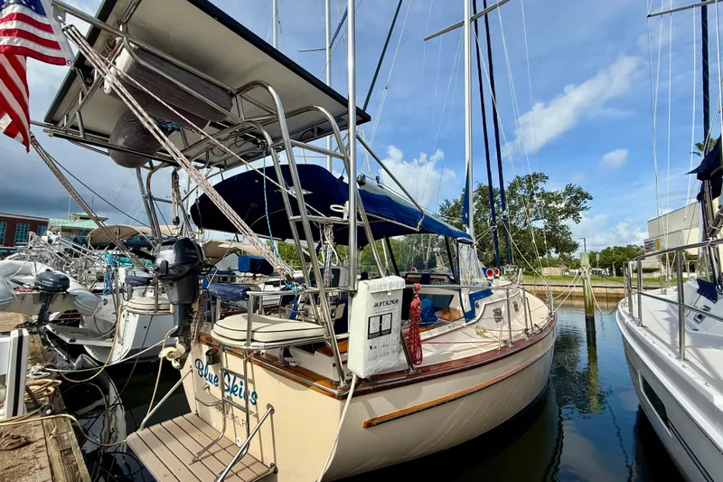 Blue Skies Yacht Photos Pics 1995 Island Packet 40 sailboat docked at marina, featuring blue canopy and American flag.