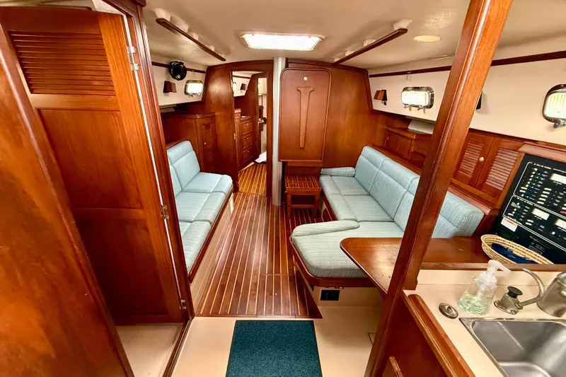 Blue Skies Yacht Photos Pics Interior of 1995 Island Packet 40 sailboat with wooden finish and blue seating.