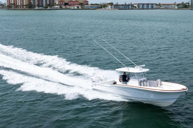  Yacht Photos Pics 2026 Buddy Davis 34 Center Console cruising on open water near coastal buildings.