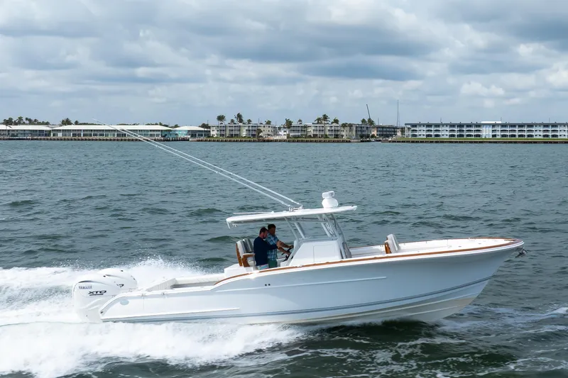  Yacht Photos Pics 2026 Buddy Davis 34 Center Console boat cruising on open water, with coastal buildings in background.