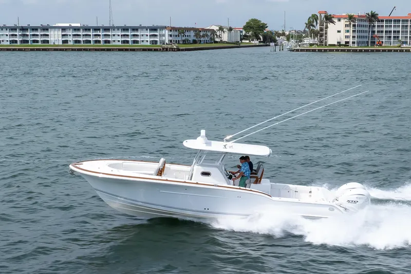  Yacht Photos Pics 2026 Buddy Davis 34 Center Console boat cruising on water near coastal buildings.