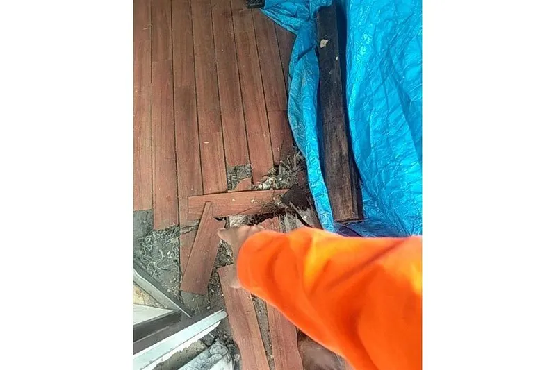  Yacht Photos Pics Person in orange points at wooden planks and blue tarp on the ground.