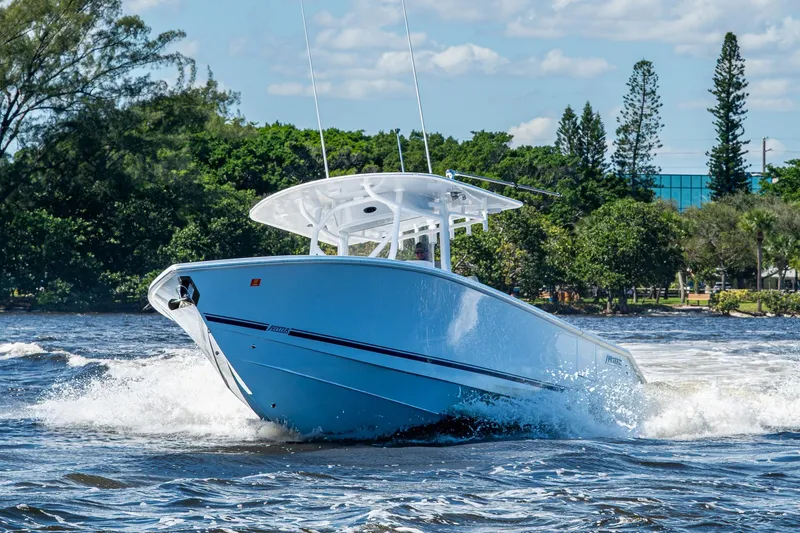  Yacht Photos Pics 2022 Jupiter 32 boat cruising on a sunny day with lush greenery in the background.