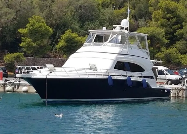 Bouki Yacht Photos Pics 2006 Bertram 670 yacht docked in serene marina with lush greenery.