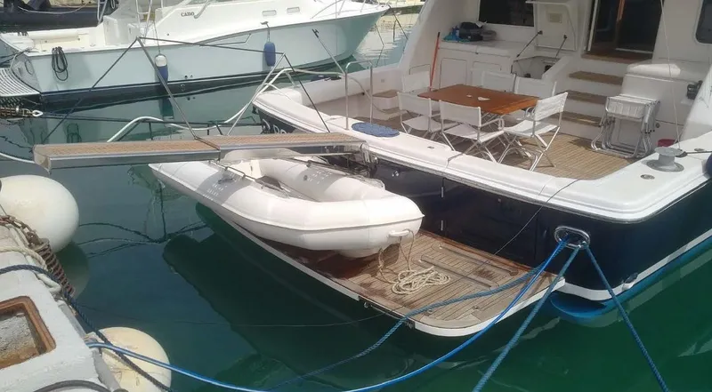 Bouki Yacht Photos Pics Bertram 670 yacht, 2006 model, docked with inflatable boat and outdoor seating area.