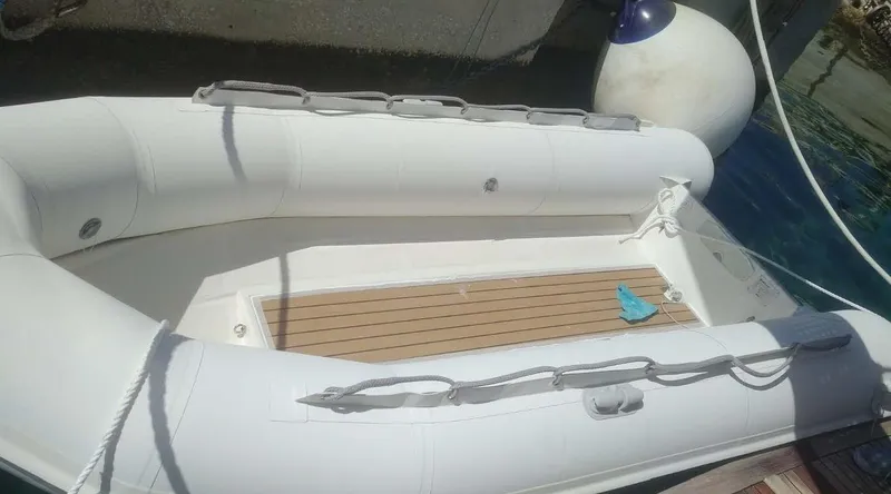 Bouki Yacht Photos Pics White inflatable boat docked, Bertram 670 model, 2006, with wooden floor panel.
