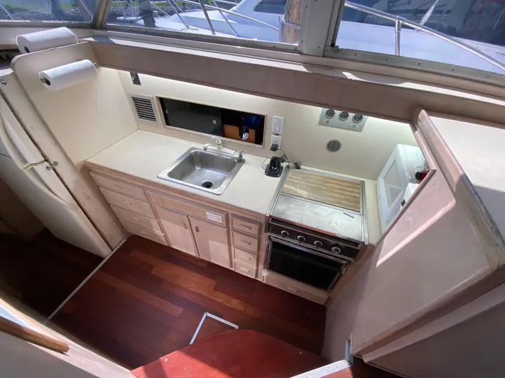  Yacht Photos Pics 1982 Bertram 46.6 War Wagon yacht kitchen with sink, stove, and wooden flooring.