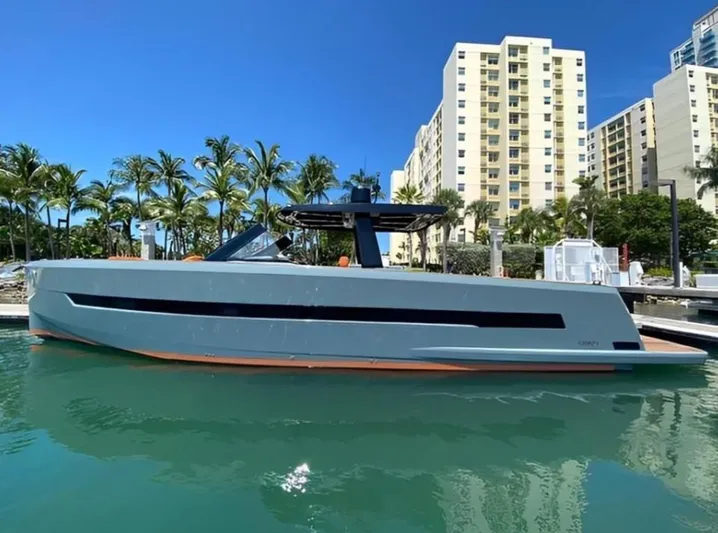 One Love Yacht Photos Pics 2019 Fjord 52 Open yacht docked, with palm trees and buildings in the background.