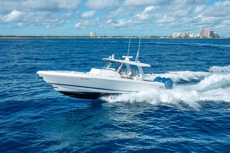  Yacht Photos Pics 2023 Intrepid 427 Nomad SE cruising on blue ocean with city skyline in background.
