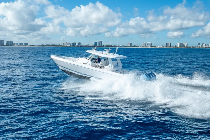  Yacht Photos Pics 2023 Intrepid 427 Nomad SE cruising on open ocean with city skyline in background.