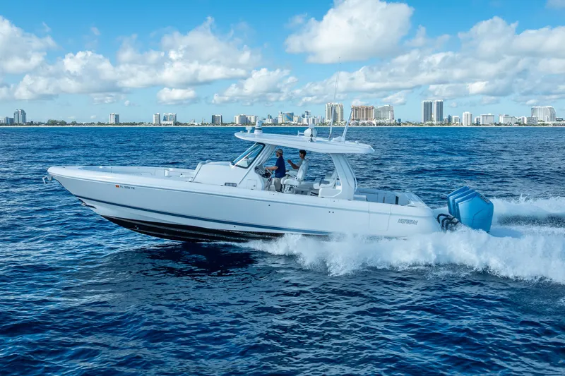  Yacht Photos Pics 2023 Intrepid 427 Nomad SE cruising on blue ocean with city skyline in background.