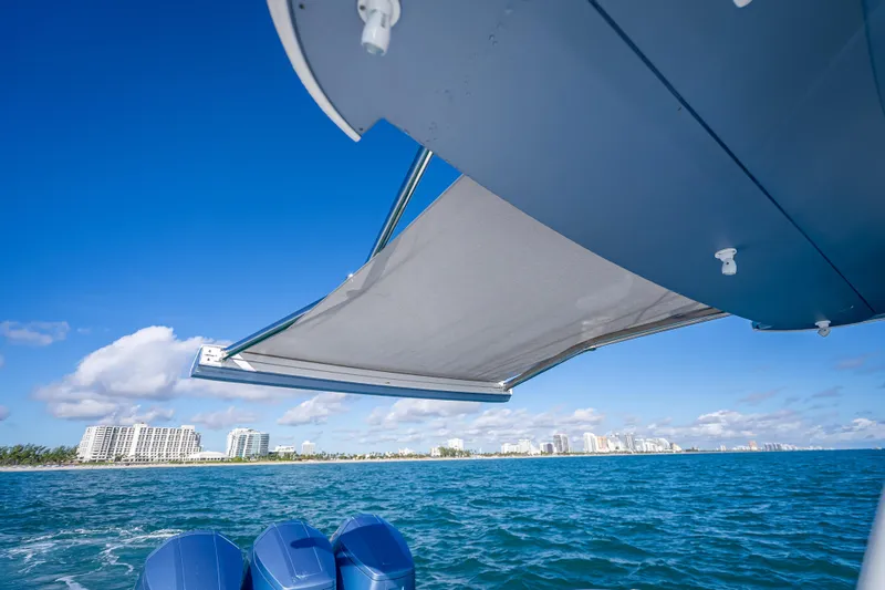  Yacht Photos Pics 2023 Intrepid 427 Nomad SE boat with awning, ocean view, and city skyline.