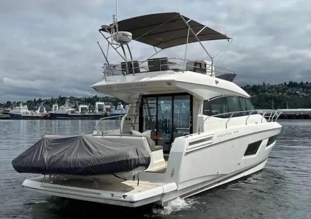 R & R Yacht Photos Pics 2015 Prestige 420 yacht on water, covered tender, overcast sky, marina in background.