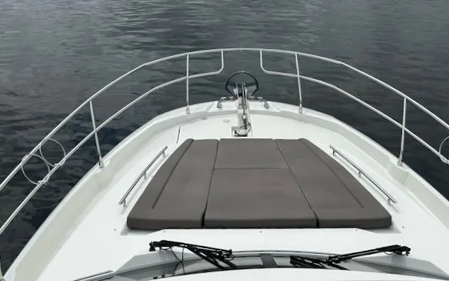 R & R Yacht Photos Pics Bow view of 2015 Prestige 420 yacht with cushioned sunbathing area on calm water.